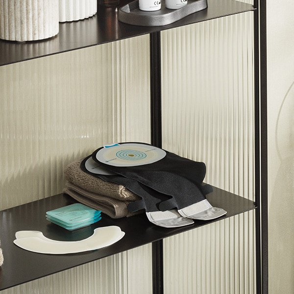 SenSura Mio Black ostomy bag placed on shelf with running shoes and water bottle in the background.